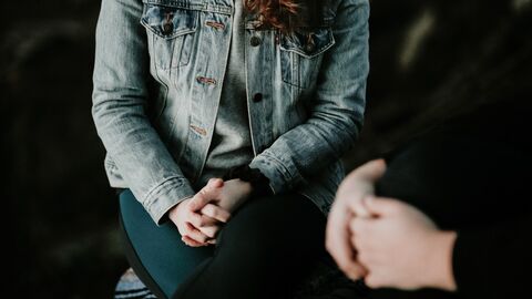 Zwei Personen sitzen mit Händen im Schoß nebeneinander. Zwei Personen sitzen mit Händen im Schoß nebeneinander.